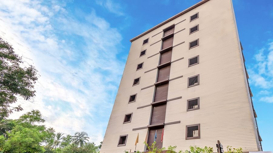Facade view of Oriental Aster, Mumbai, against the sky, with plants and trees on the sides. 