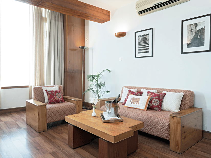 Living room with sofa seating, wooden coffee table, city view window and wooden flooring at Clarks Amer, Jaipur.