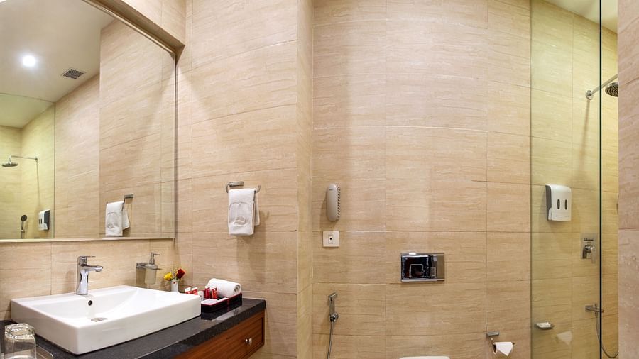 Modern bathroom with shower cubicle, sink, wall-mounted toiletries, and toilet - Lords Eco Inn Shapar Rajkot