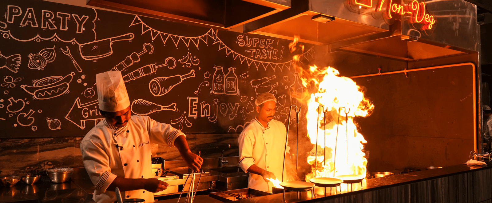 Chefs preparing food in live kitchen with open counter at Pravasa Hotel, Kolhapur.