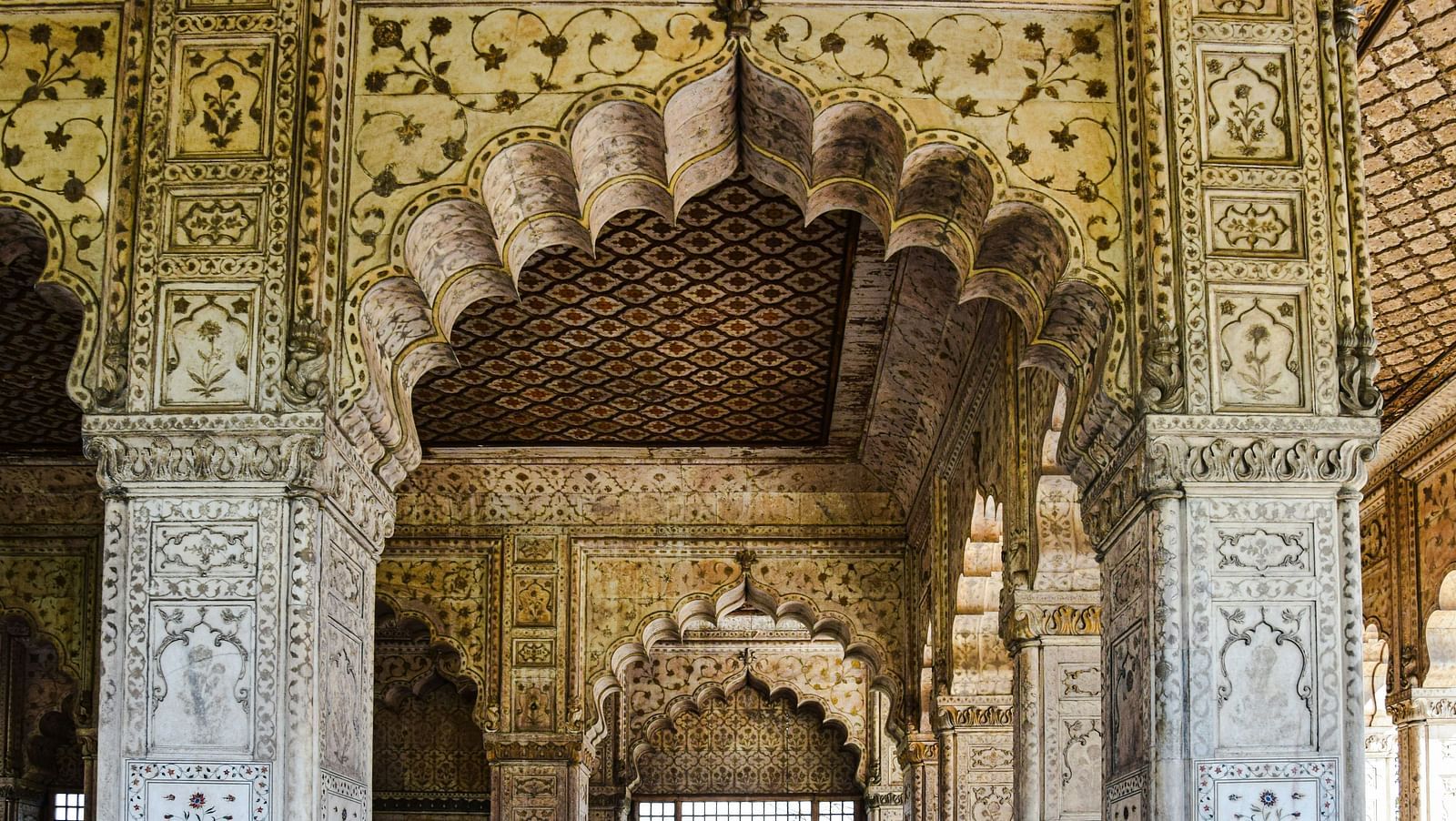 Intricately carved arches and pillars frame a doorway at the Red Fort, showcasing Mughal architectural detail.