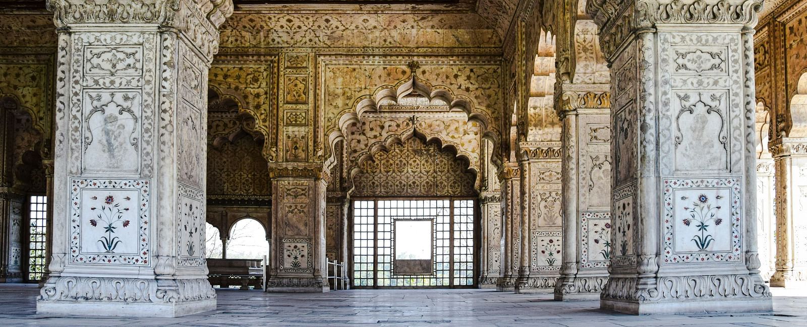 Intricately carved arches and pillars frame a doorway at the Red Fort, showcasing Mughal architectural detail.