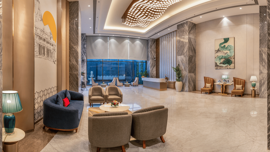 Lobby with a plush blue sofa, comfortable seating, and a striking ceiling light feature at Lords Inn Somnath, a grand welcome space.