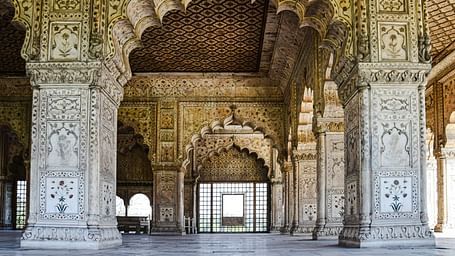 Intricately carved arches and pillars frame a doorway at the Red Fort, showcasing Mughal architectural detail.