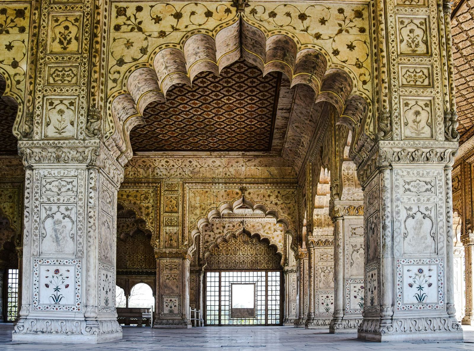 Intricately carved arches and pillars frame a doorway at the Red Fort, showcasing Mughal architectural detail.