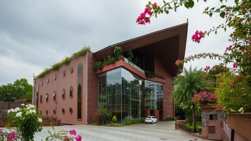 Uday Palace Convention Centre facade under a cloudy sky with bougainvilleas blooming in the surroundings
