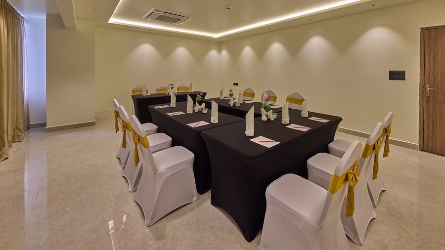 A beautifully lit banquet hall with a navy blue-draped long table surrounded by chairs wrapped in white covers