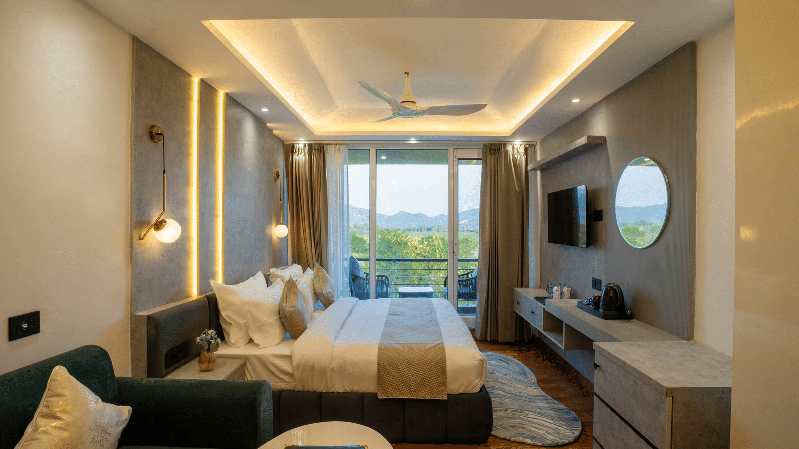 The guest room at Sukoon by the Ganges features a luxurious bed, sofa seating, and a lovely view through the glass balcony door.