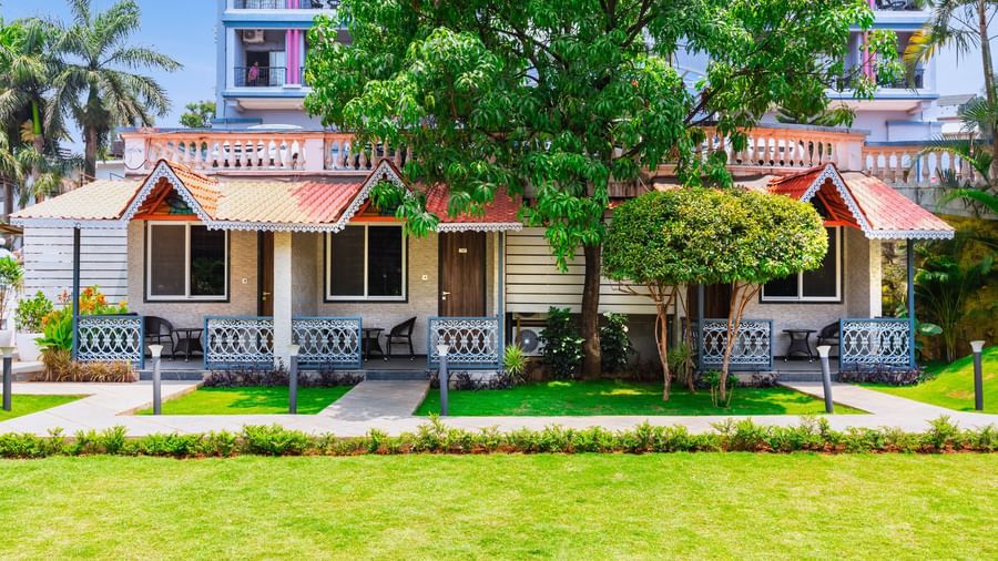 Garden view at Mayur Retreat with lush green lawns in front of charming red-roofed villas and shaded balconies.