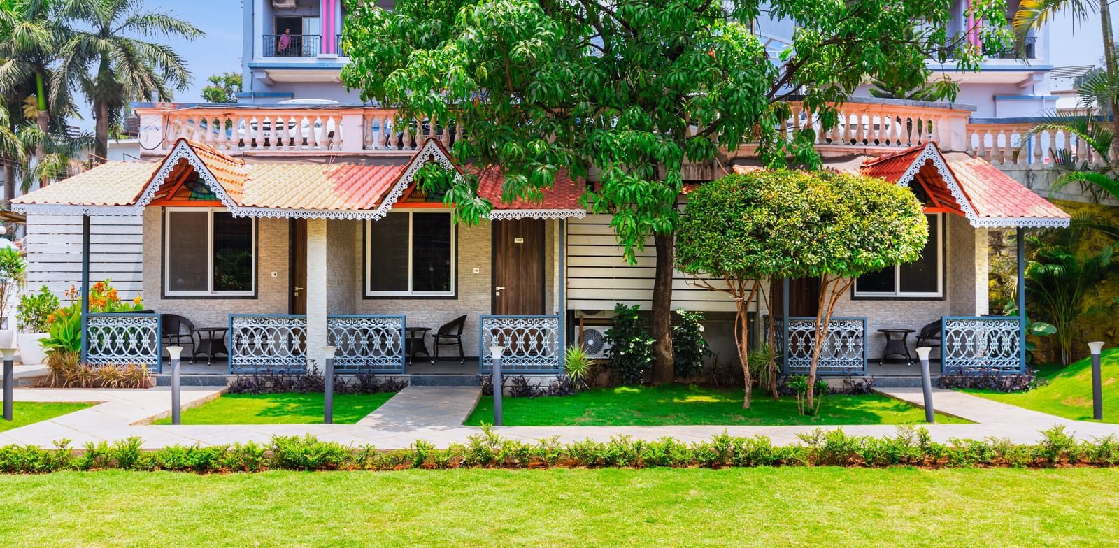 Garden view at Mayur Retreat with lush green lawns in front of charming red-roofed villas and shaded balconies.