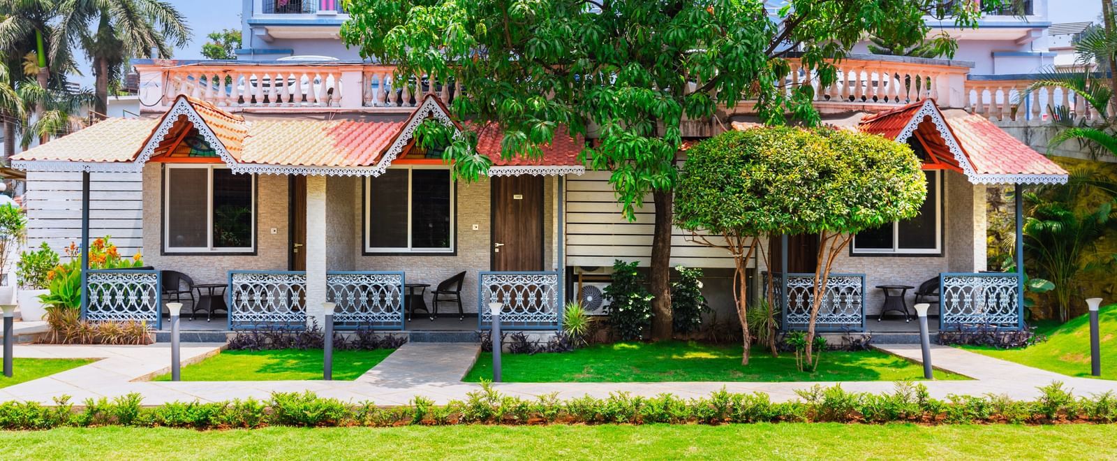 Garden view at Mayur Retreat with lush green lawns in front of charming red-roofed villas and shaded balconies.