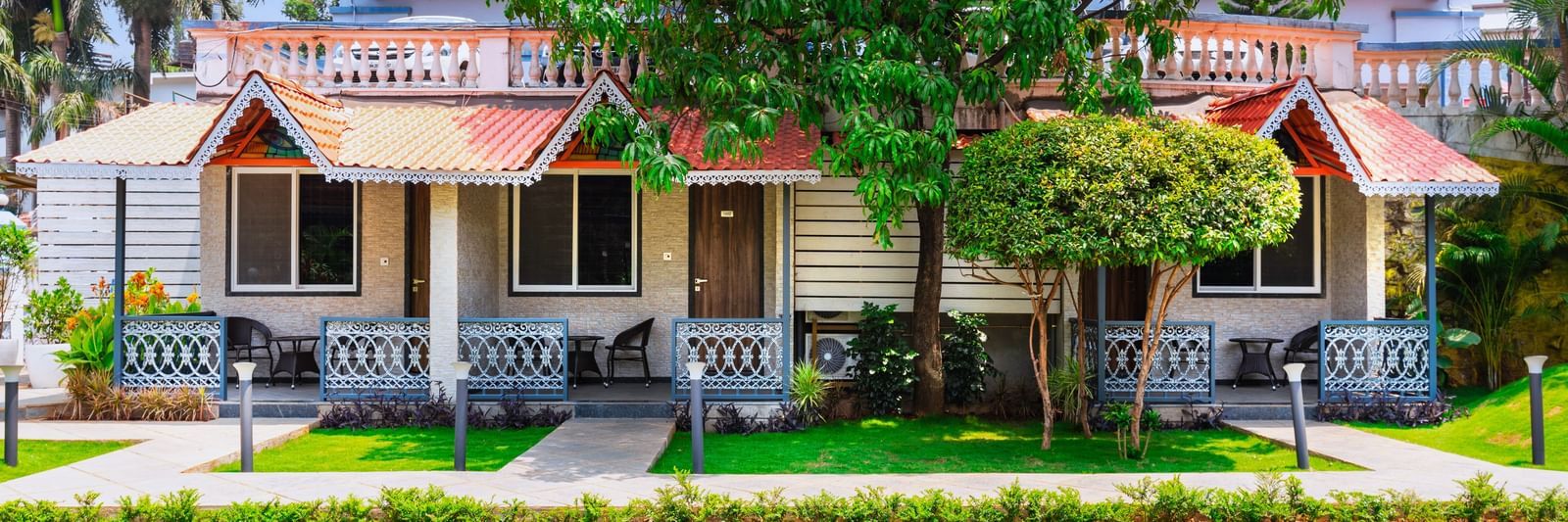 Garden view at Mayur Retreat with lush green lawns in front of charming red-roofed villas and shaded balconies.