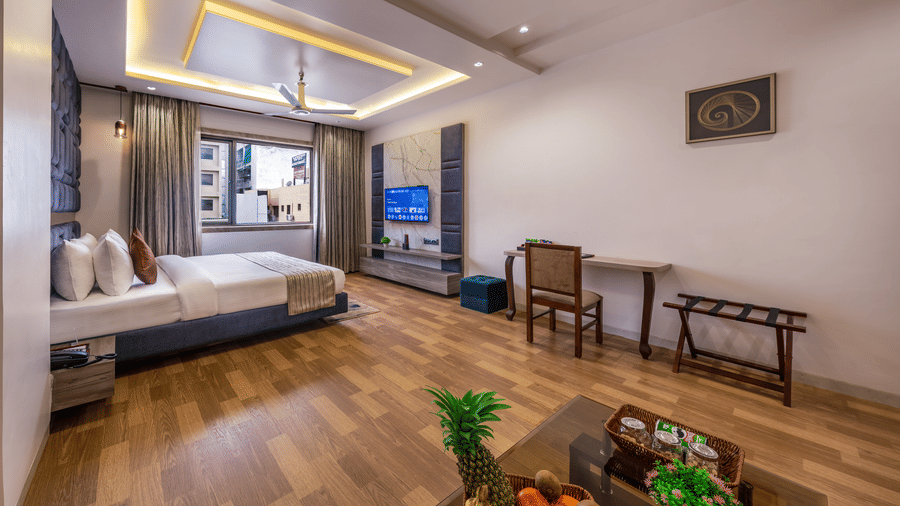 Spacious suite at Lords Inn Sangam, Bhopal with a bed, seating area, dining table with fresh fruit, and large windows overlooking the city.