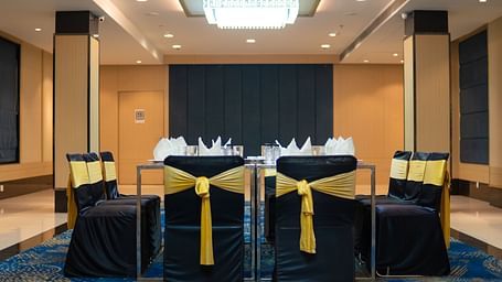 a hall with a square table and decorated chairs surrounding it - Jardin Hotels, Indore