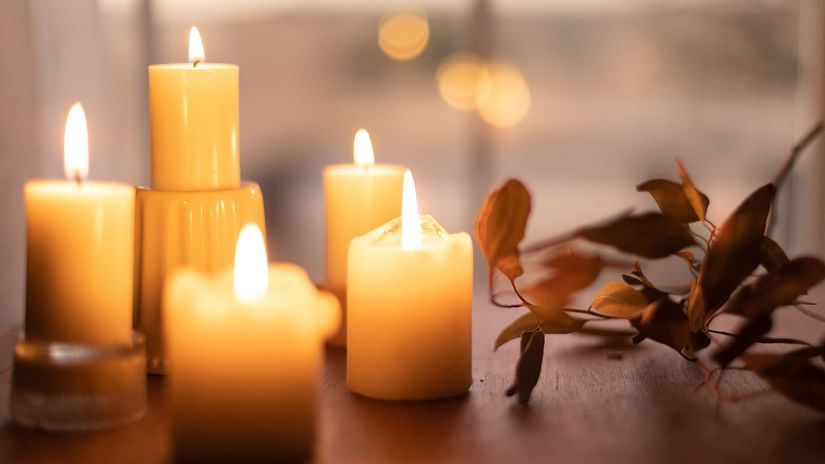 many candles lit and kept on a table with a dried flower next to it