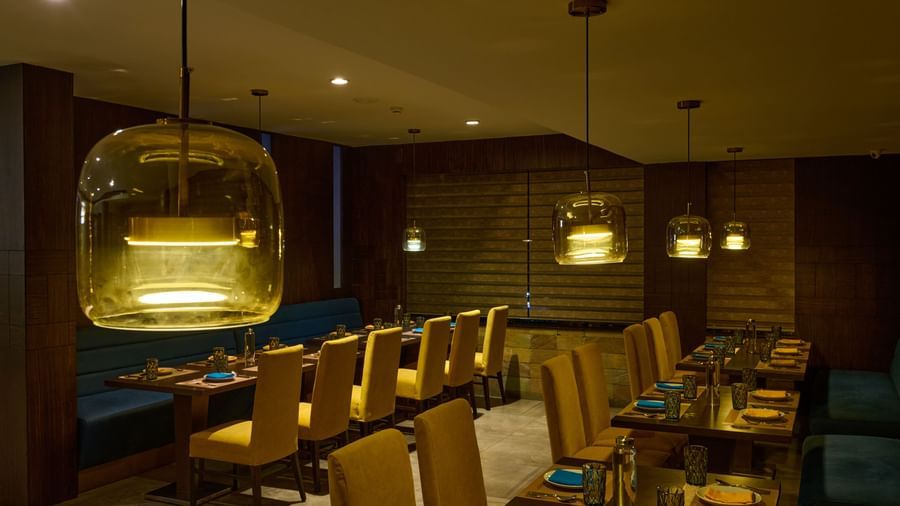 Elegant restaurant at Voyage Milestone Hotel and Banquet with hanging lights and cozy seating.