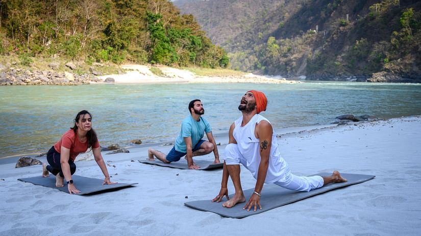 Visitors performing yoga on a beach - Neemrana's Glasshouse on The Ganges