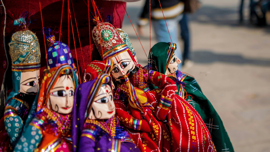 A vibrant display of traditional, handcrafted string puppets hangs for sale at an outdoor market stall.