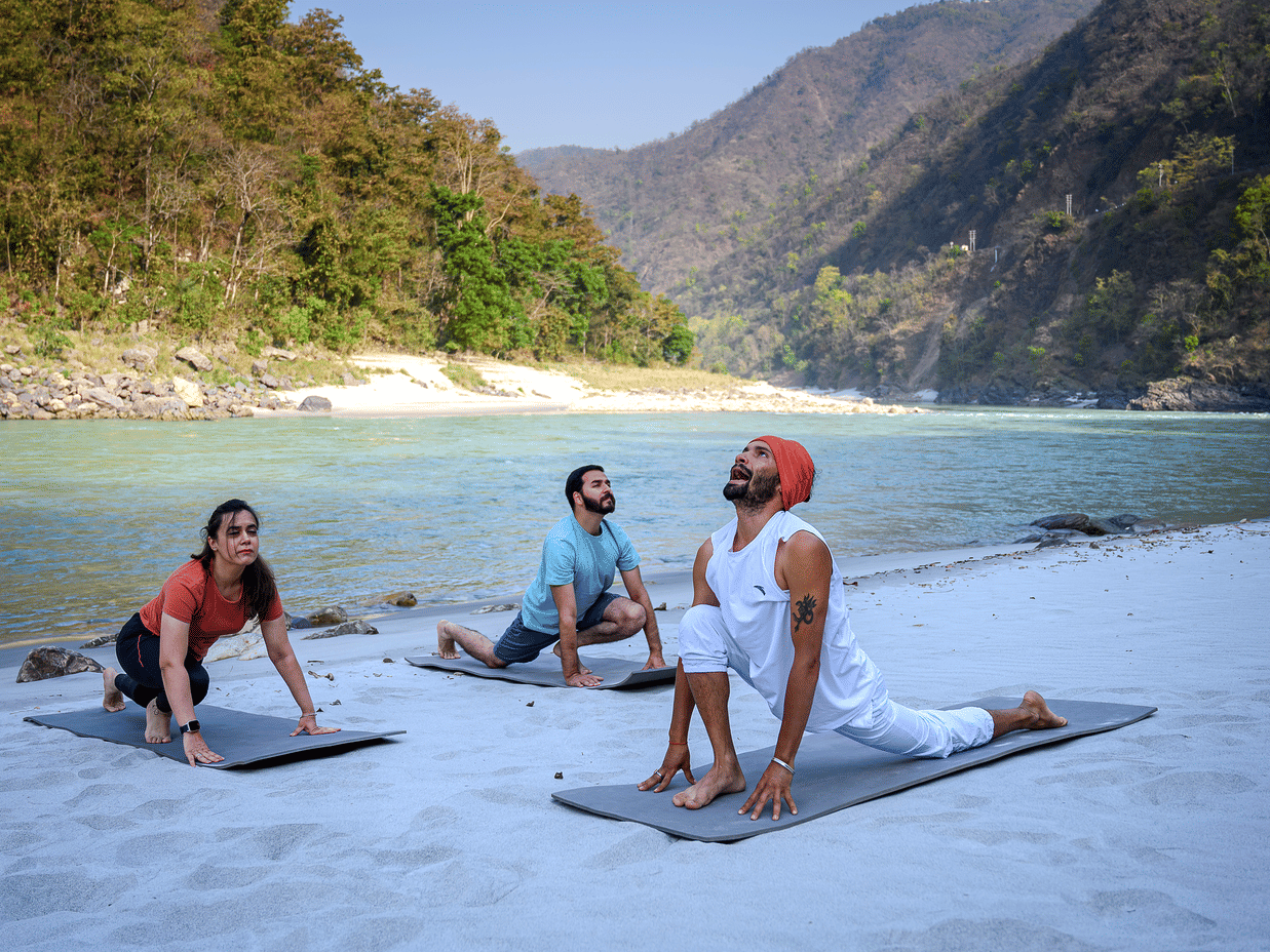 Visitors performing yoga on a beach - Neemrana's Glasshouse on The Ganges