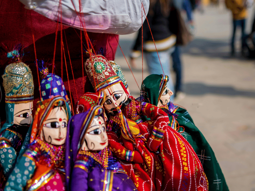 A vibrant display of traditional, handcrafted string puppets hangs for sale at an outdoor market stall.