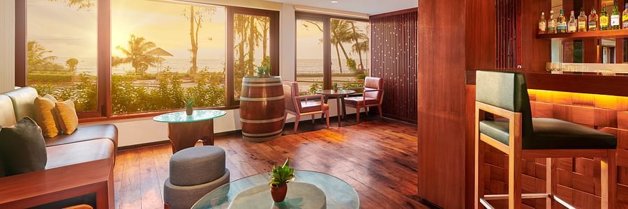 A coffee table in the centre with a leather sofa on the side inside the Upper deck Bar - The Resort, Mumbai
