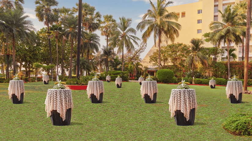 Many tables with a vase and bouquet kept on top of it on the Lawn - The Resort, Mumbai