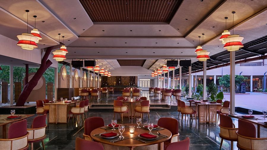 The interior of Zaika features numerous round tables with red chairs, illuminated by distinctive red and white hanging pendant lights.