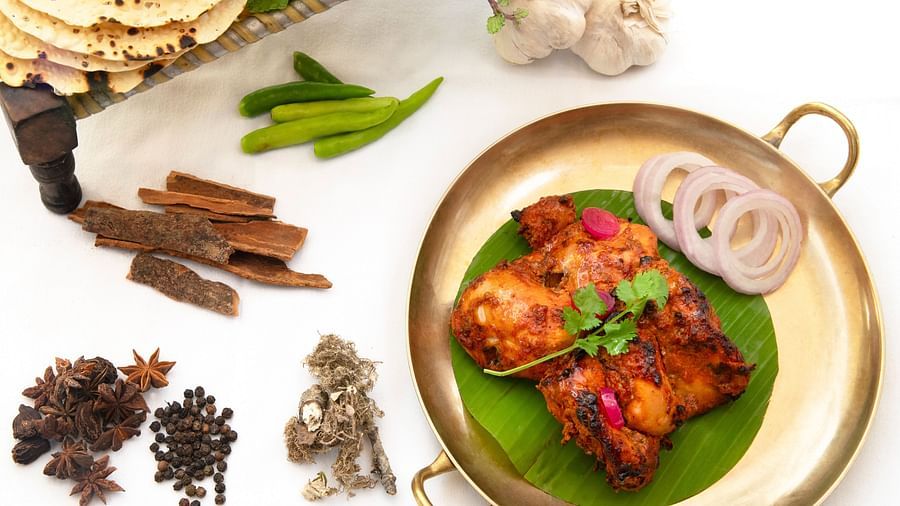 image of an indian preparation of chicken served on a banana leaf - The Claridges New Delhi