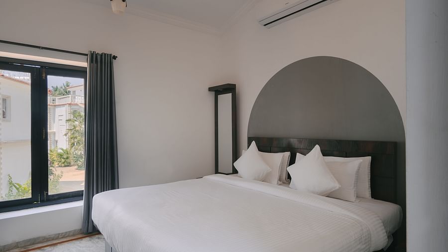 Bedroom with a stylish arched headboard and natural light in the Three BHK Deluxe Villa at Richmonde Ananta Elite, Goa.