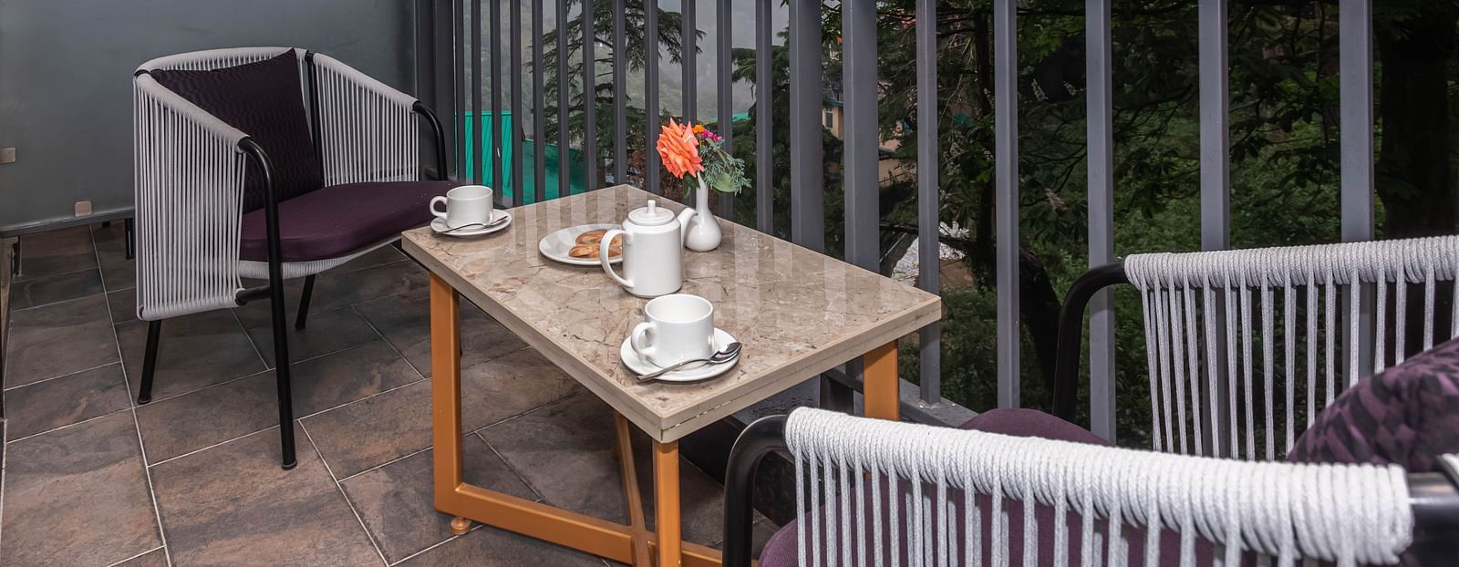 An image of a balcony of the Superior Room with chairs and table overlooking the scenic mountains - The Belvedere Himalayan Retreat, McLeodganj