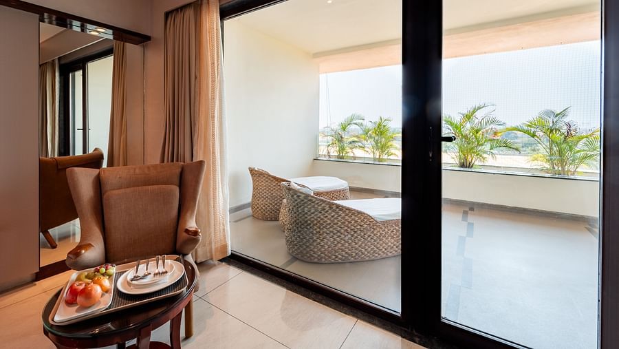 Large glass door leading to a balcony with cushioned seating to enjoy the view at Crescent Spa & Resort, Indore