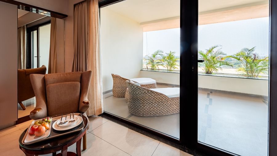 Large glass door leading to a balcony with cushioned seating to enjoy the view at Crescent Spa & Resort, Indore