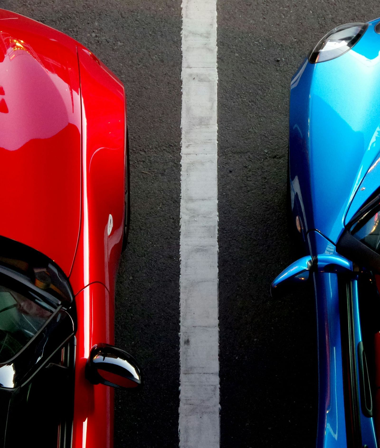 Top-down view of a red and a blue car parked in marked bays.