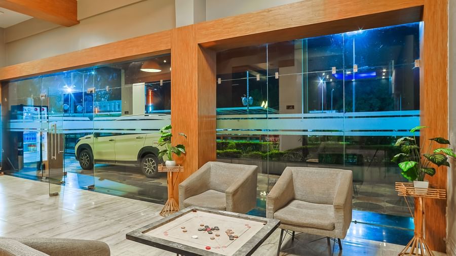 Lobby seating area with sofas, tables and large glass windows at Max Hotel Prayagraj.