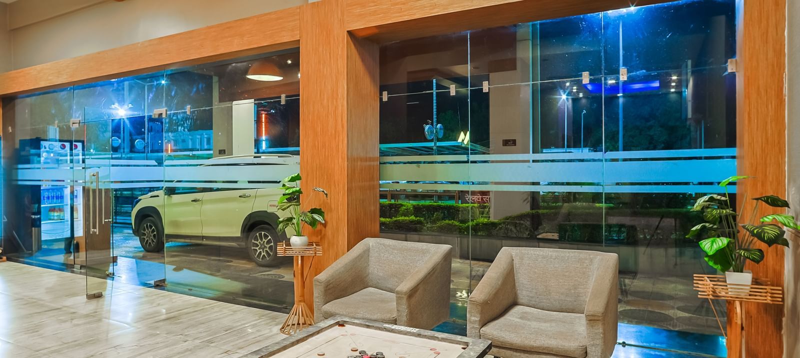 Lobby seating area with sofas, tables and large glass windows at Max Hotel Prayagraj.