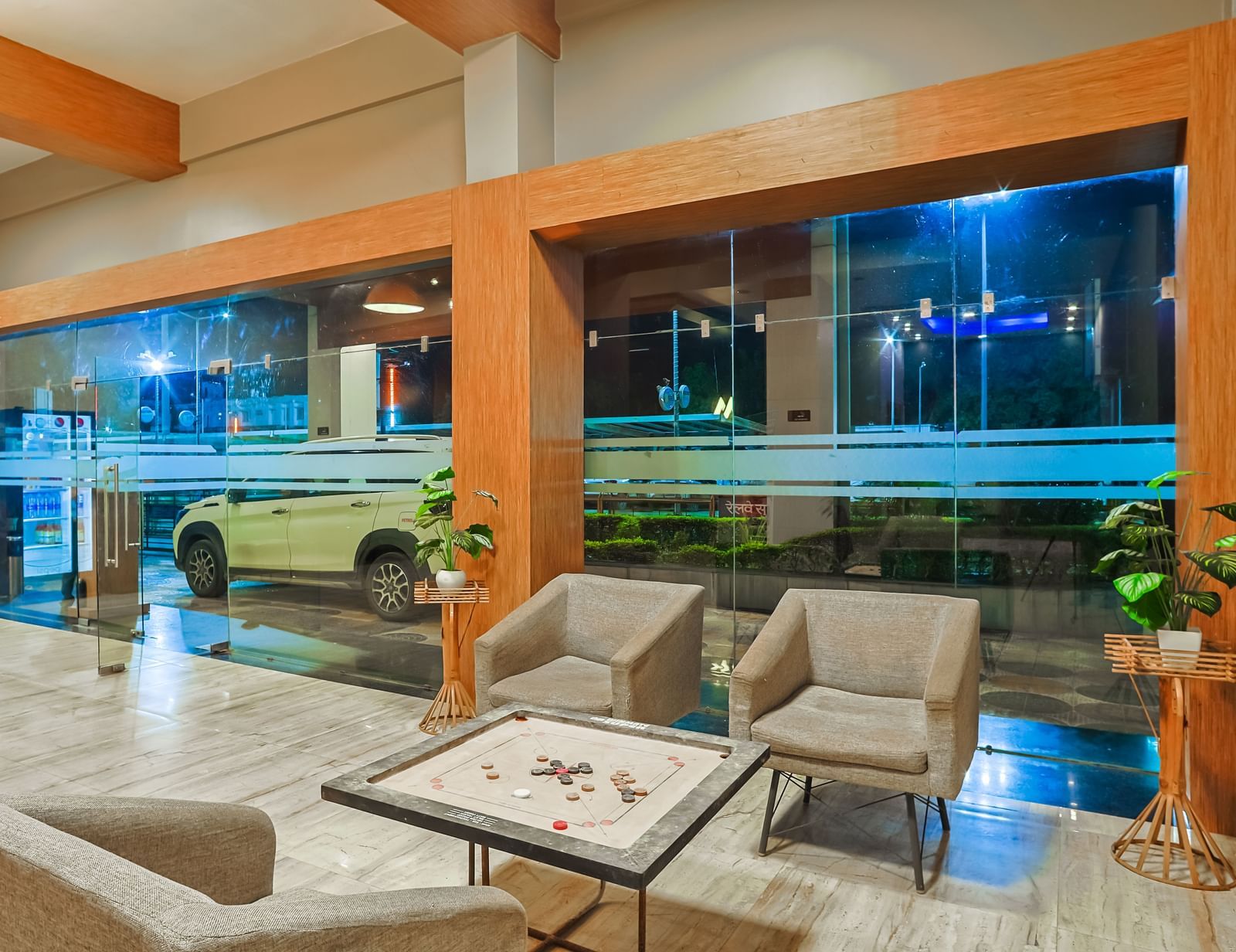 Lobby seating area with sofas, tables and large glass windows at Max Hotel Prayagraj.