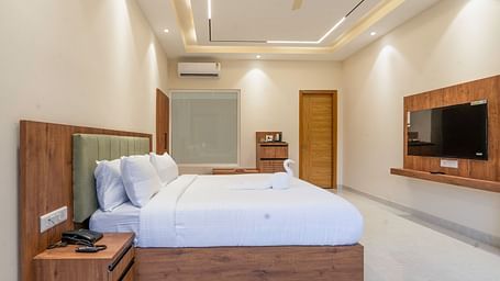 a bed, a side table, and television inside the mountain view room at Corbett Four Seasons, Ramnagar