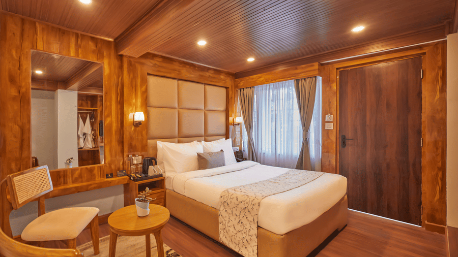A wood-clad bedroom with a large bed, wall mirrors, and warm bedside lighting | Voyage Rodhi Resort