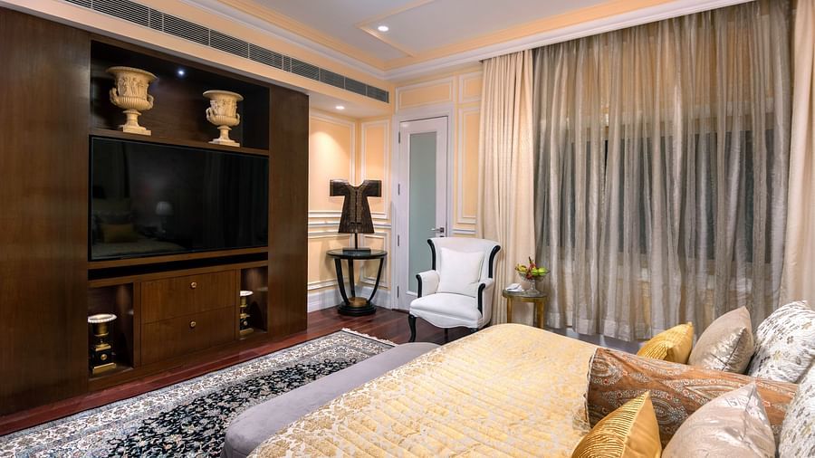 an image of our prestige estate suite with plush bedding and a wall mounted tv placed opposite to the bed - The Claridges New Delhi