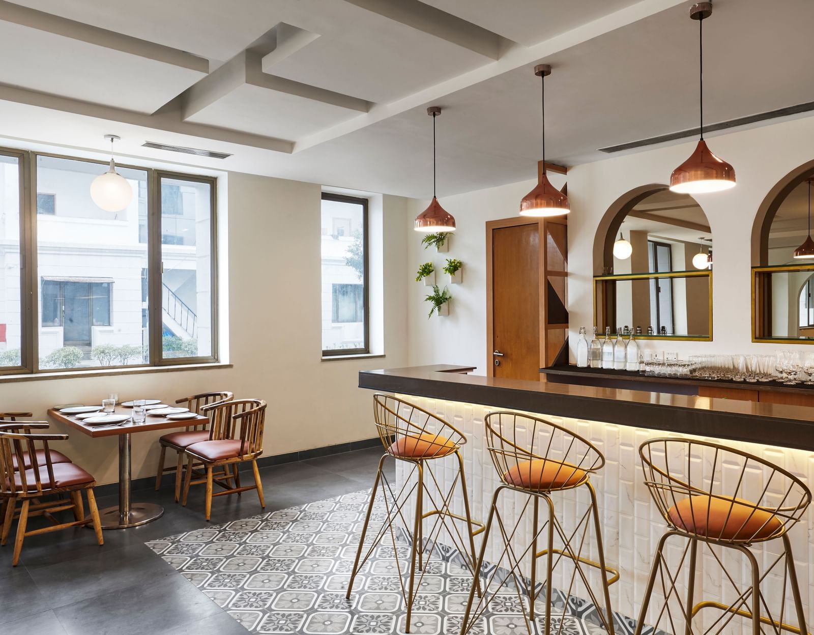 A corner view of the dining hall at Monday Hotels Mahape, Navi Mumbai, showing the bar and windows.