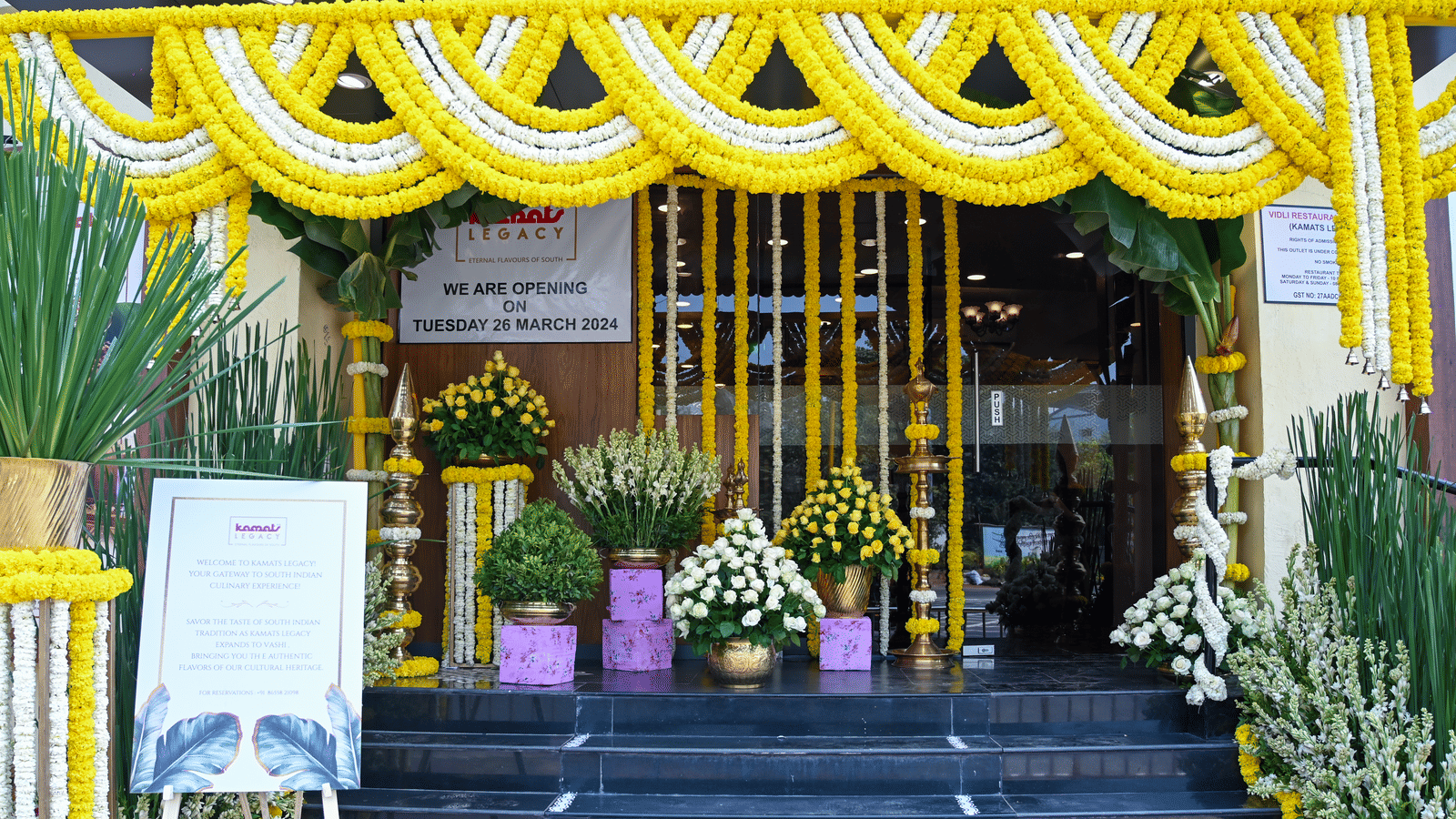 Festively adorned entrance of Kamats Legacy Vashi with vibrant flowers and greenery, creating an inviting and celebratory ambience.