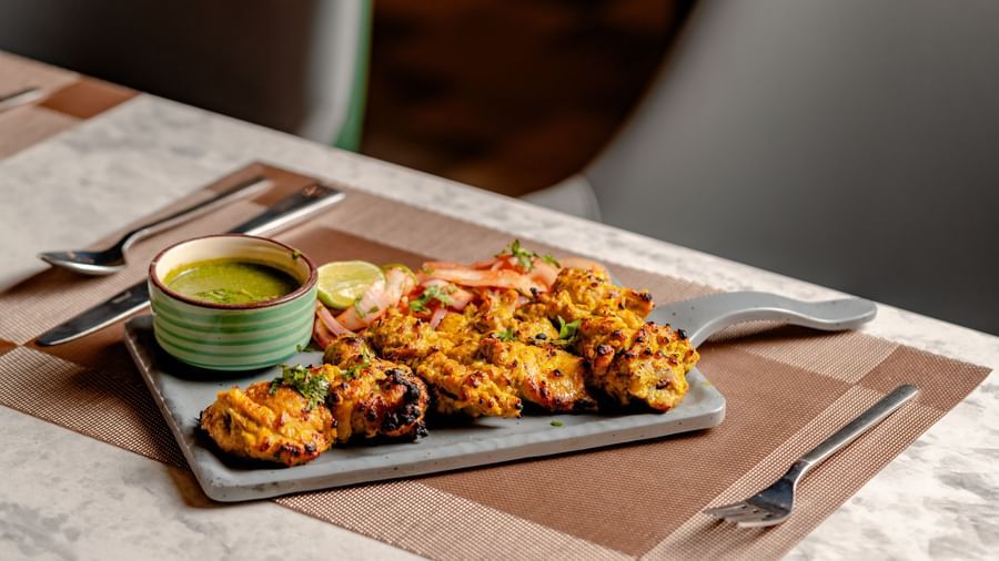 Plate of Indian snacks, with a green chutney dipping sauce | Pravasa Hotel, Vijayapura