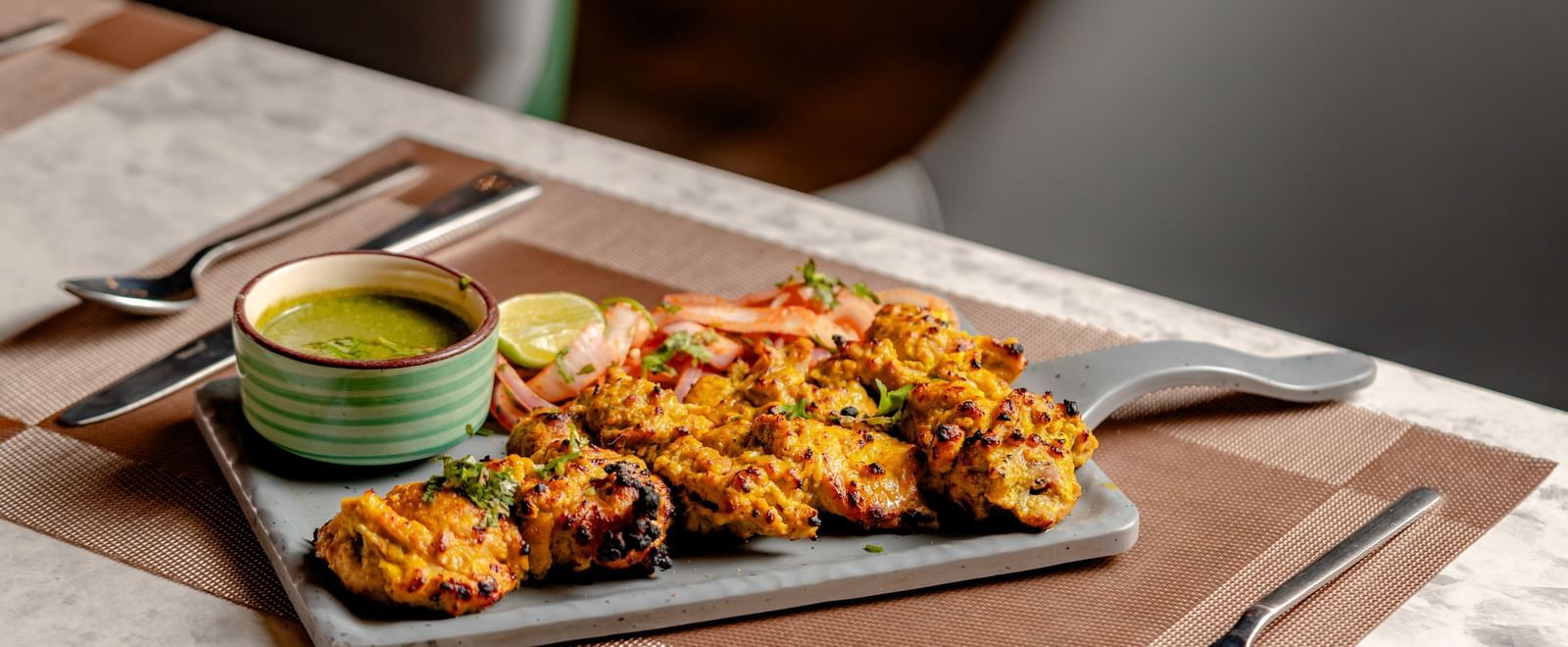 Plate of Indian snacks, with a green chutney dipping sauce | Pravasa Hotel, Vijayapura