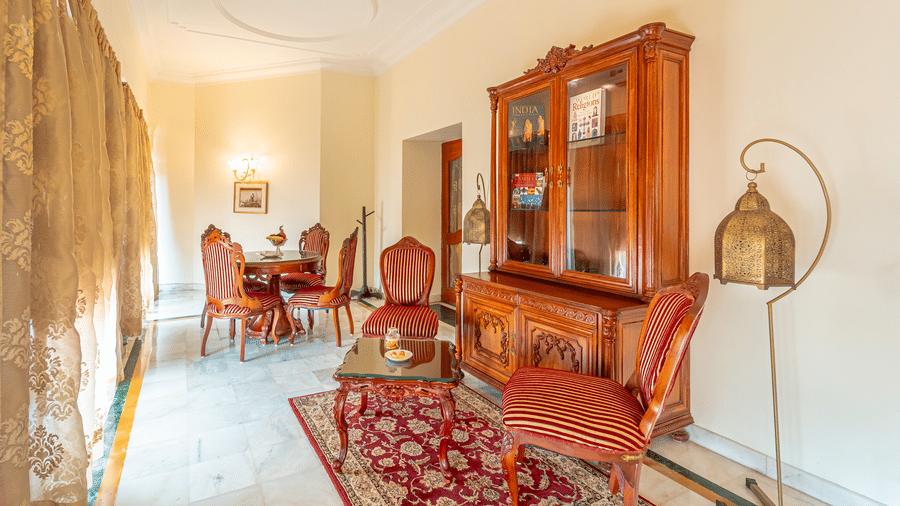 An elegant private dining or meeting room within the Presidential Suite at Noor-Us-Sabah Palace, with a classic wooden sideboard and red upholstery.