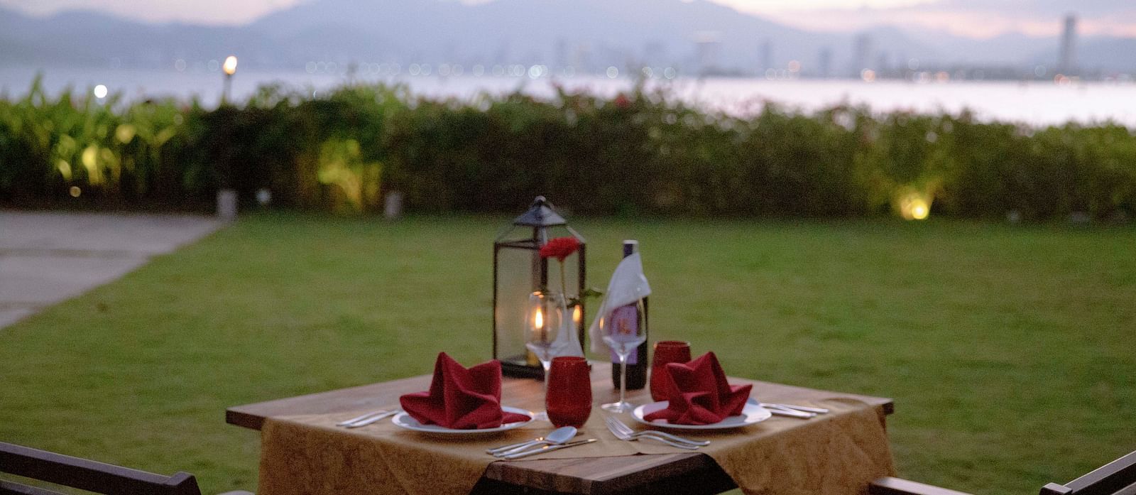 A romantic dinner setup for two on the lawn at dusk - Alibu Resort Nha Trang
