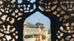 A view via a well carved lattice window of an elaborate edifice