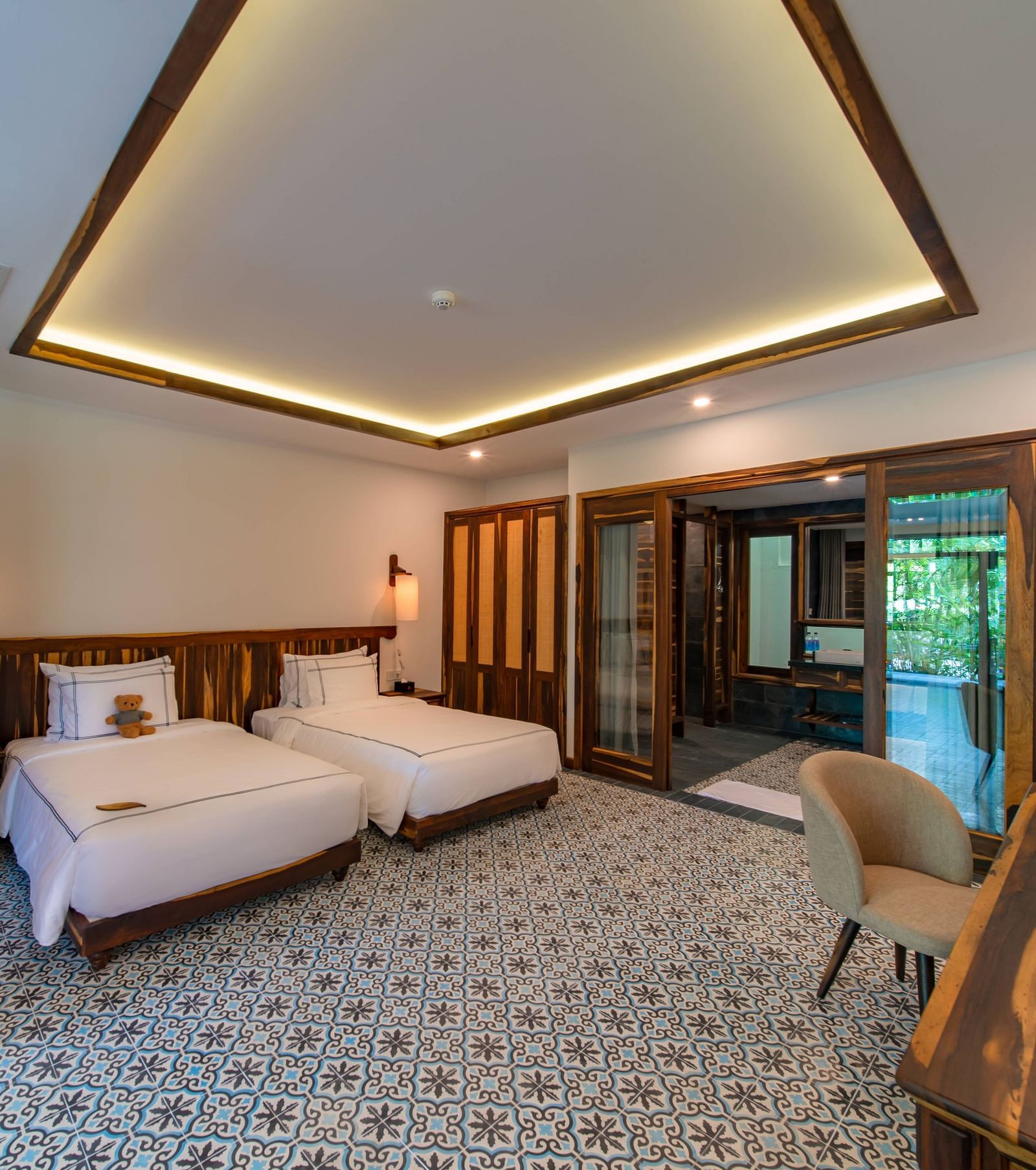 Twin beds with white bed sheets facing a rustic wooden desk in our room - Alibu Resort Nha Trang