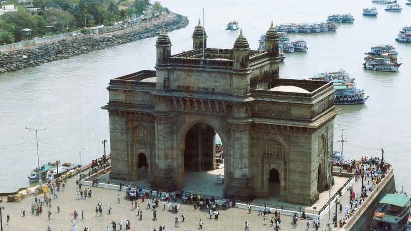 Historic waterfront monument surrounded by visitors, boats, and harbour views during the day