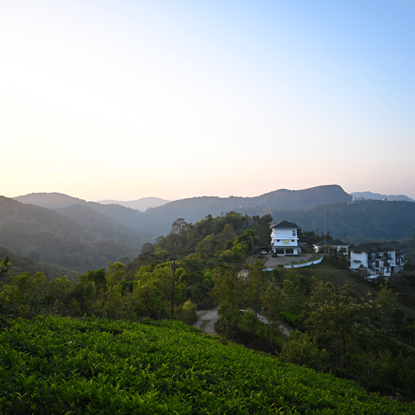 A wide landscape view of rolling green hills and a small white building under a clear sky at dusk | Abad Silvermist, Vagamon