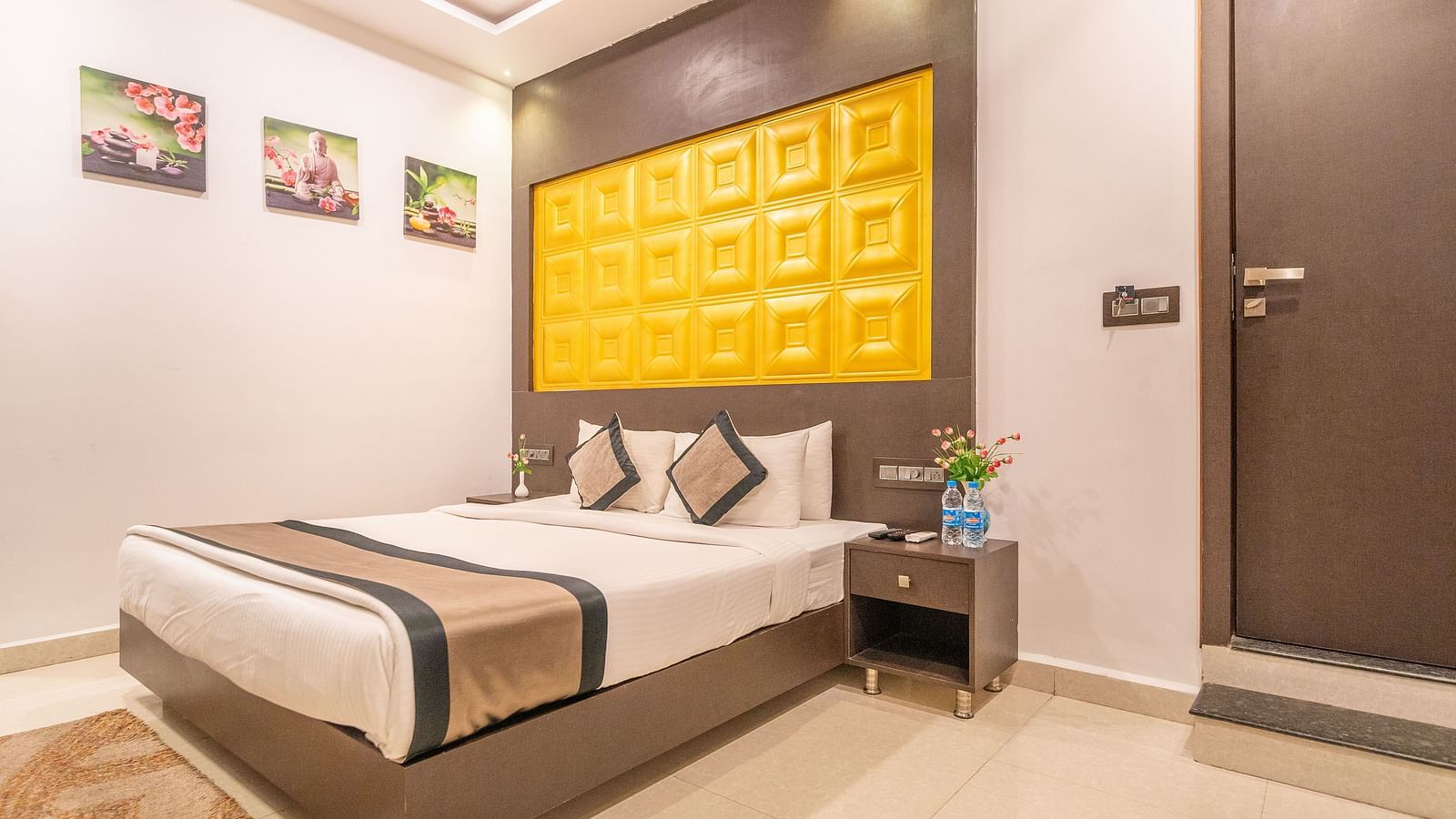 Image of a room with a bed and three flower prints on the side at Parampara Residency, Kushalnagar.